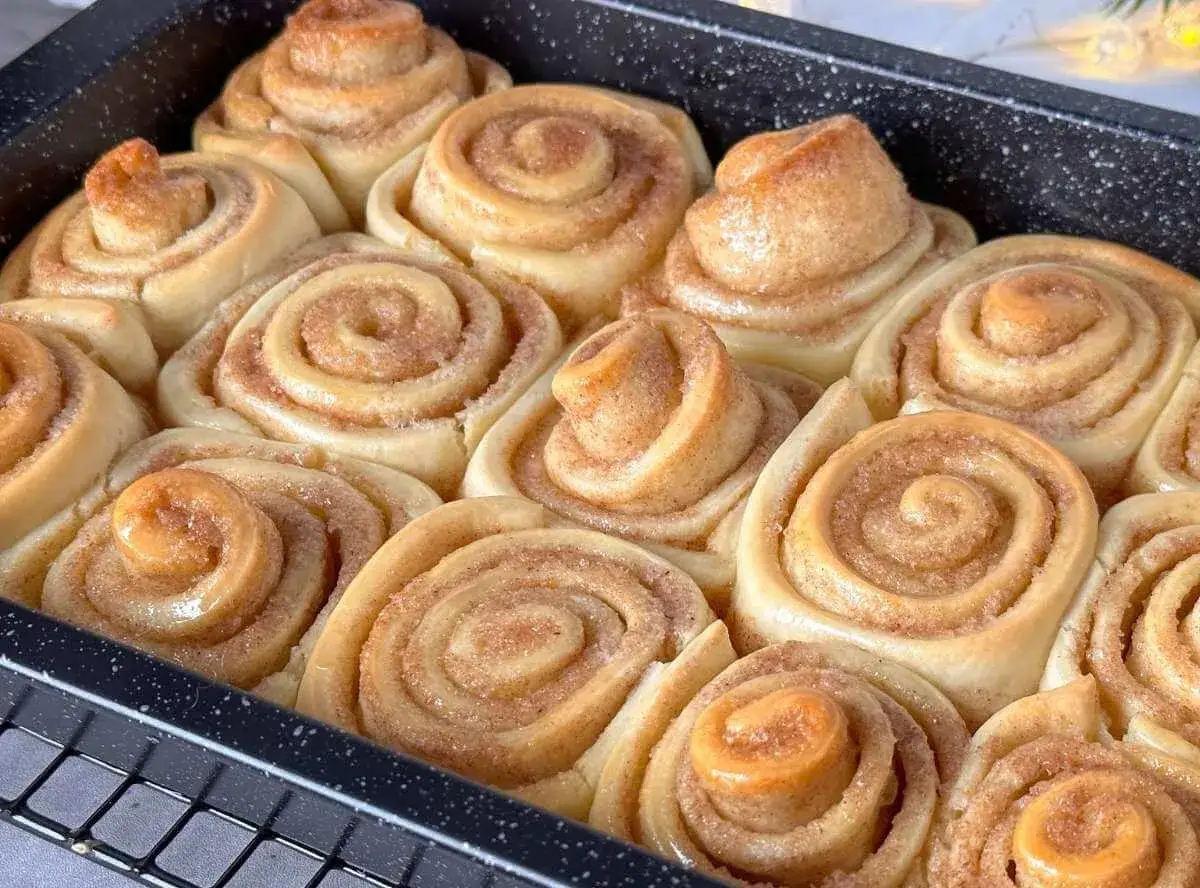Frisch gebackene Zimtschnecken in einer Backform, goldbraun und duftend.