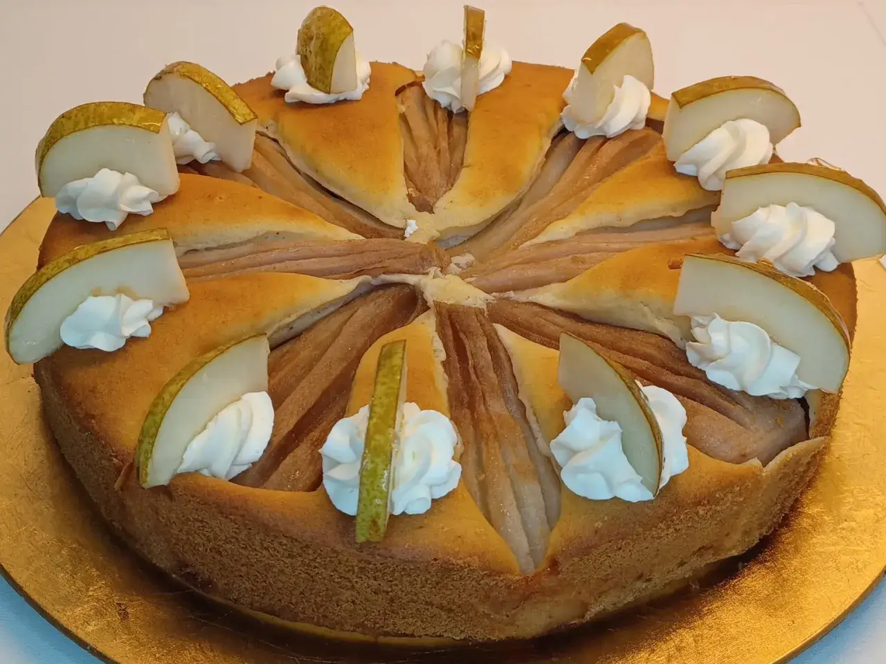 Ein köstlicher Birnenkuchen, verziert mit Sahnetupfern und frischen Birnenspalten. Perfekt für ein Birnenkuchen Rezept.