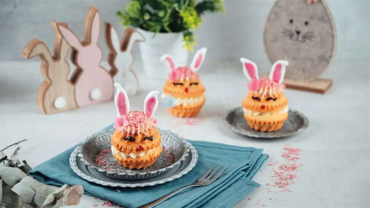 Drei s&uuml;&szlig;e Mini Gugelhupf dekorieren als Osterhasen mit rosa Ohren und pinker Kokosraspelspr&uuml;hhaube.