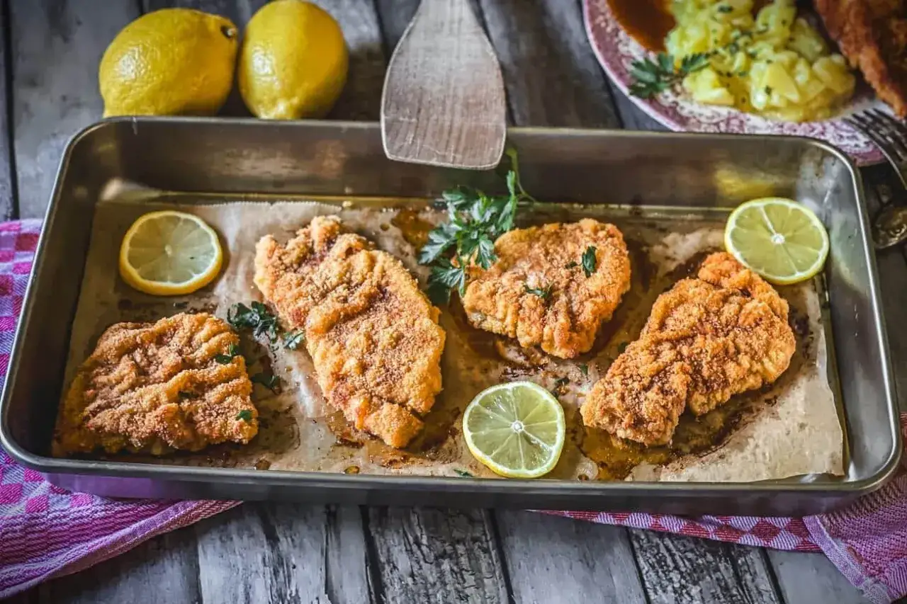 Saftiges Schnitzel im Backofen, goldbraun paniert, mit frischer Petersilie und Zitronenspalten garniert. Ein Genuss!