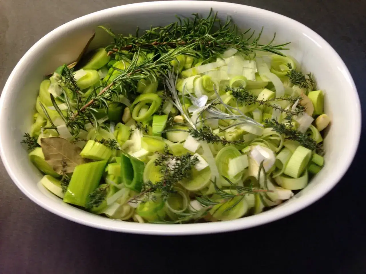 Frischer Lauch, Kräuter und Lorbeerblätter in einer Schüssel – bereit für leckere Lauch Rezepte.