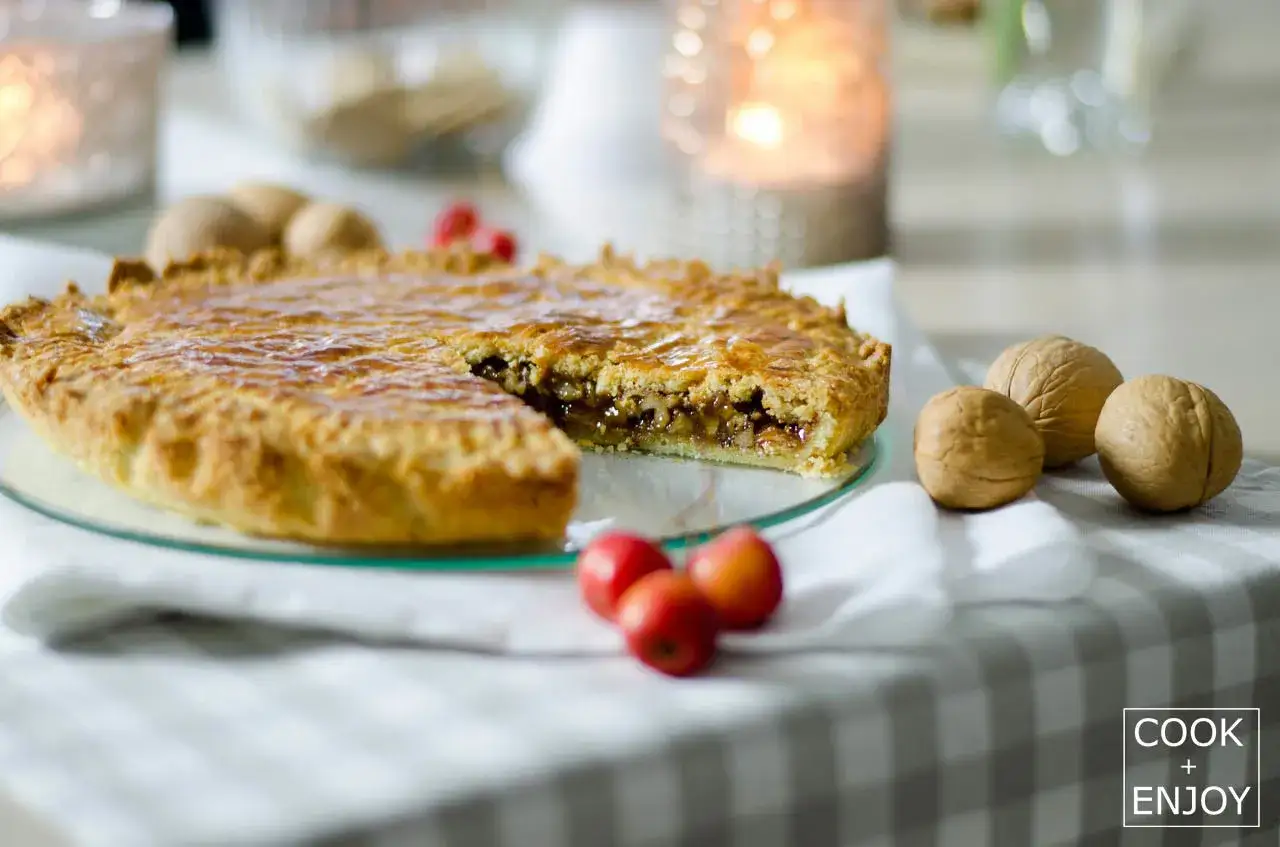 Eine k&ouml;stliche Engadiner Nusstorte mit goldbraunem Teig und nussiger F&uuml;llung, dekoriert mit Waln&uuml;ssen und roten Beeren.