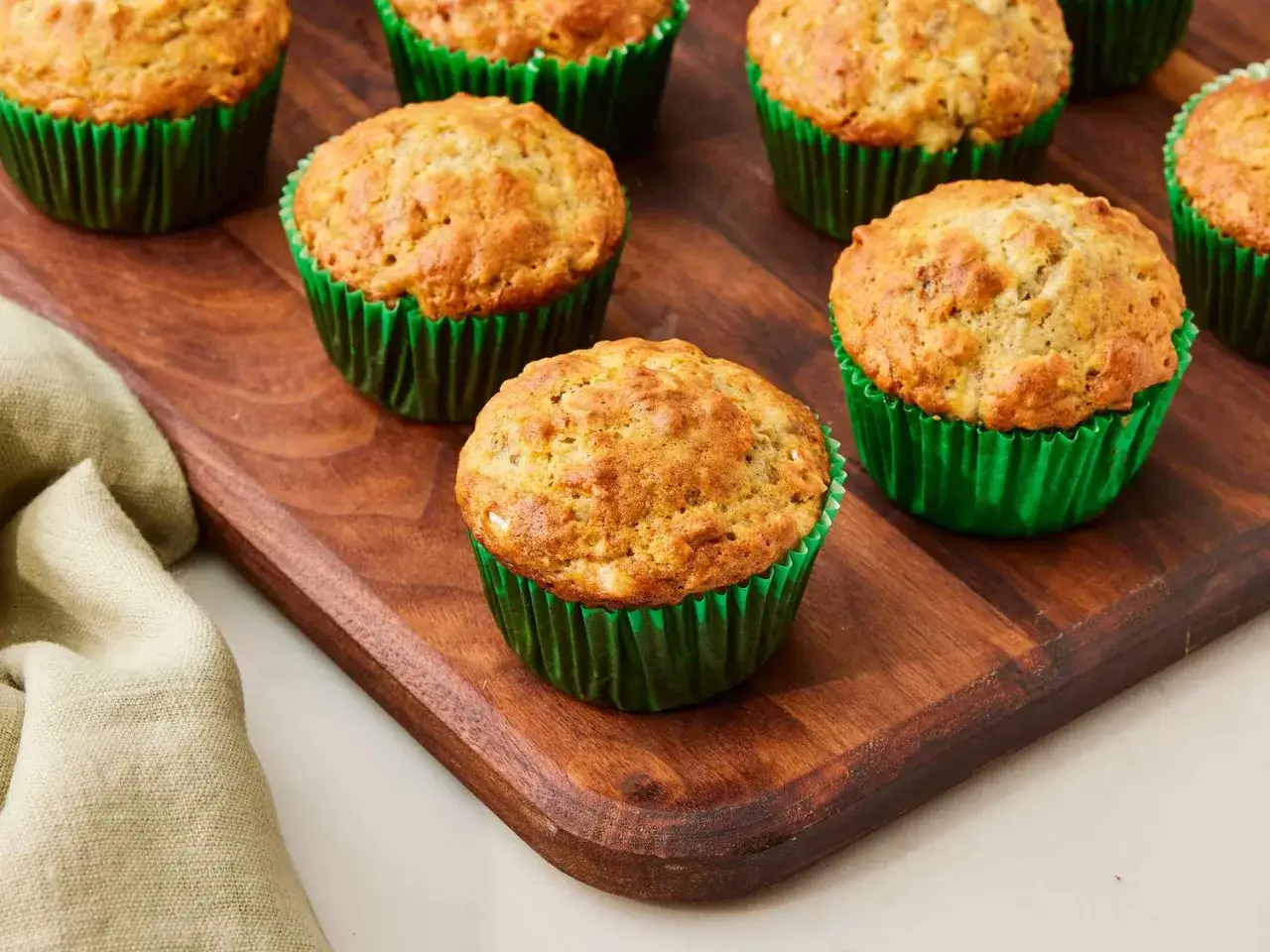 Saftige Muffins ohne Zucker, gebacken in gr&uuml;nen Papierf&ouml;rmchen, liegen auf einem Holzbrett.