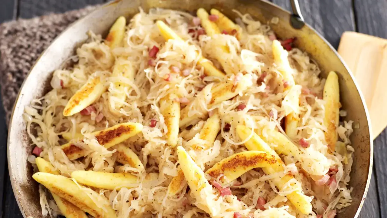 Schupfnudeln mit Sauerkraut und Speckw&uuml;rfeln in einer Pfanne, ein deftiges Gericht.