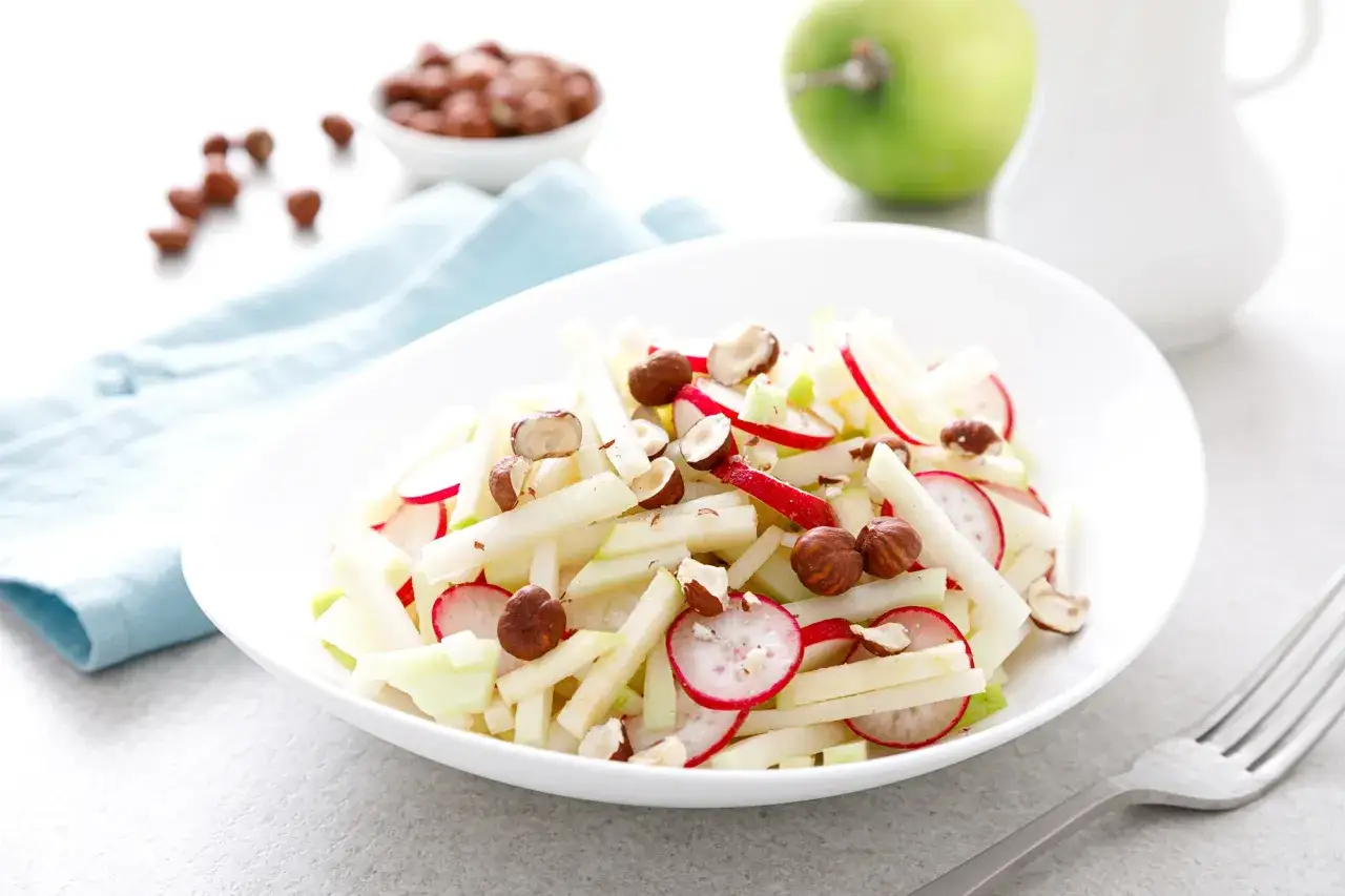 Frischer Kohlrabi Salat mit Radieschen und Haselnüssen, garniert mit Apfelstücken. Ein leichter Genuss.