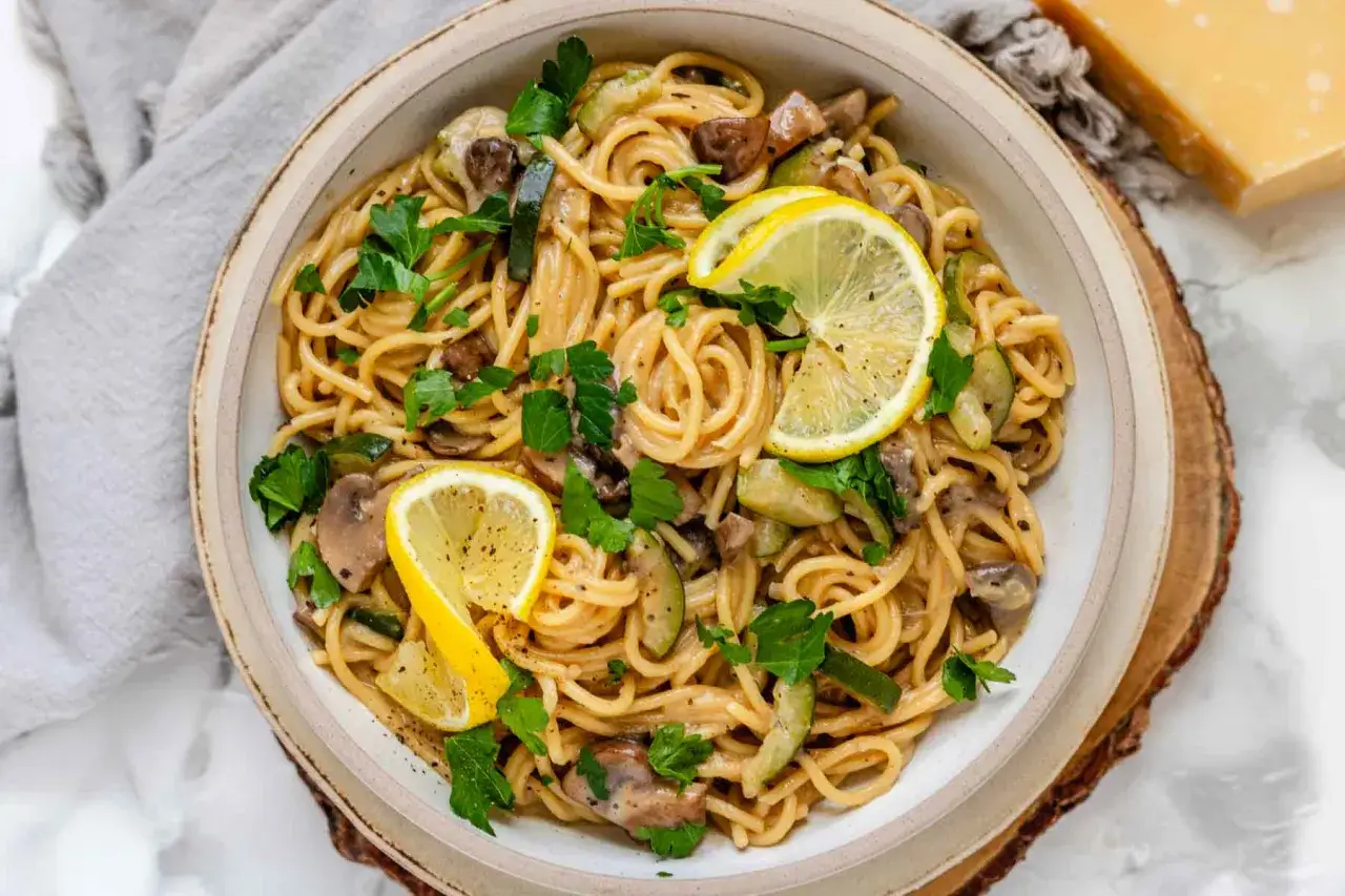 Cremige Pasta mit Pilzen und Zucchini-Nudeln, garniert mit Zitronenspalten und Petersilie. Ein köstliches Gericht!