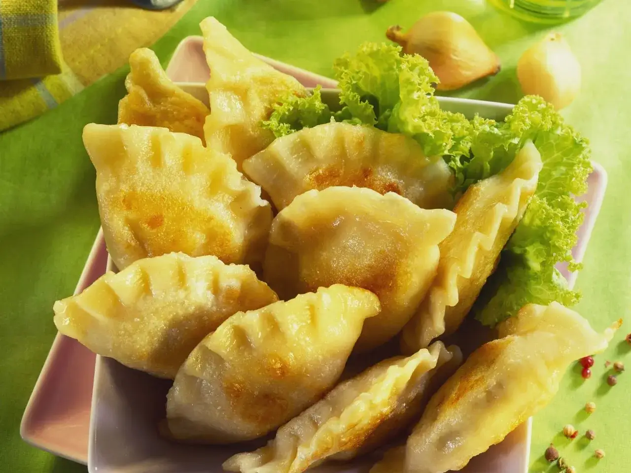 Goldbraune Pierogi, frisch zubereitet nach einem einfachen Pierogi Rezept, serviert mit Salat und Zwiebeln.