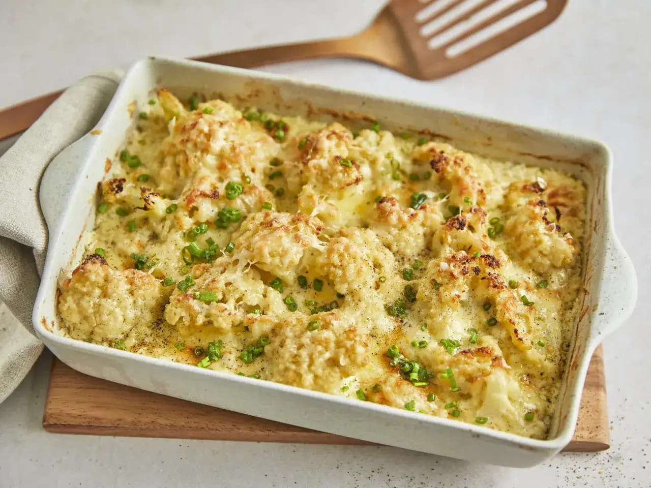 Herzhafter blumenkohl auflauf mit K&auml;se &uuml;berbacken und frischen Kr&auml;utern bestreut, bereit zum Servieren.