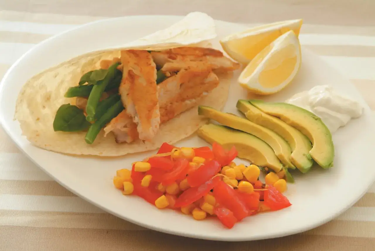 Ein k&ouml;stlicher Thunfisch-Wrap mit gr&uuml;nen Bohnen, Mais, Tomaten, Avocado, Zitrone und einem Klecks Sour Cream.