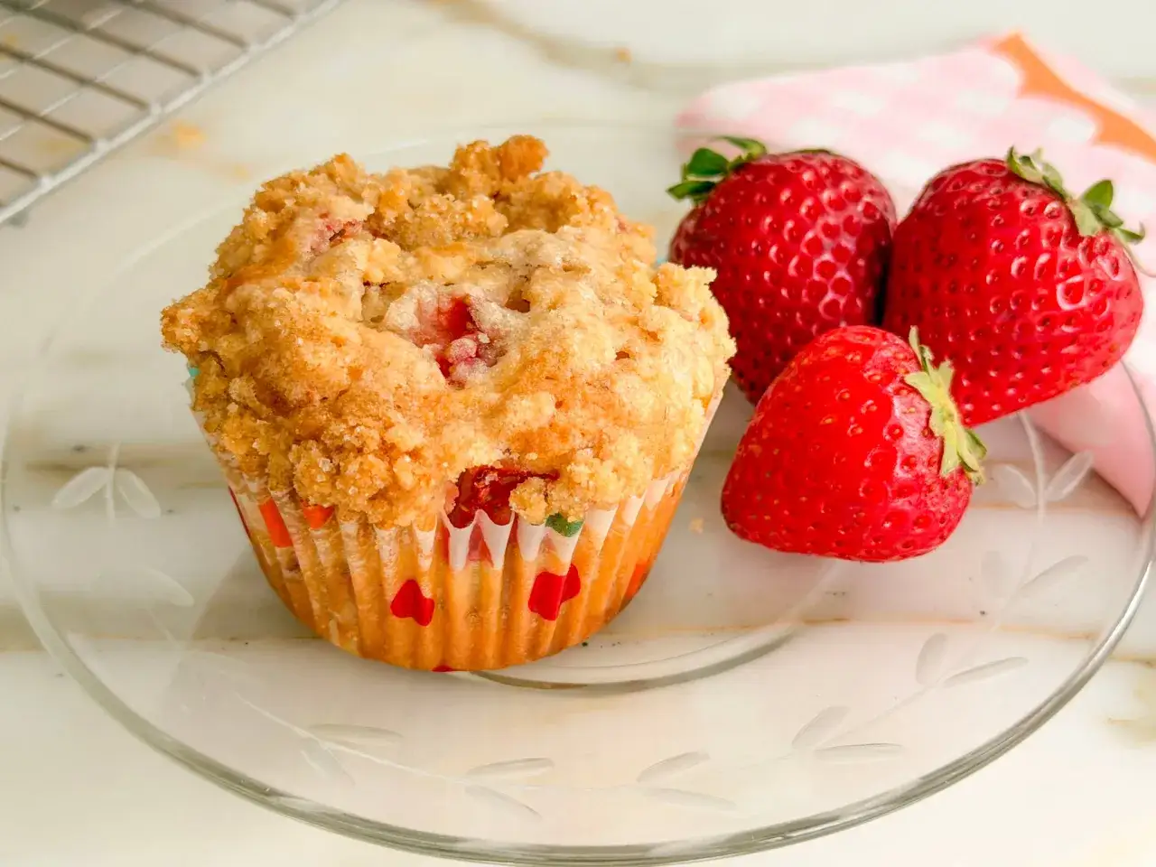 Ein saftiger Muffin mit Obst und Joghurt, garniert mit frischen Erdbeeren auf einem Teller.