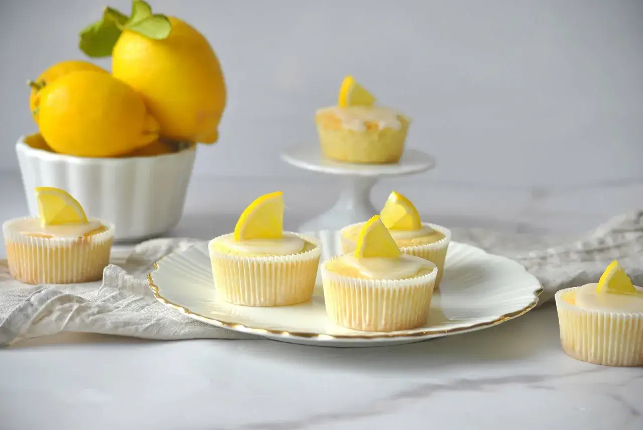 Erfrischende Zitronenmuffins mit Zuckerguss und Zitronenspalten, inspiriert von einem Zitronenmuffins Rezept.