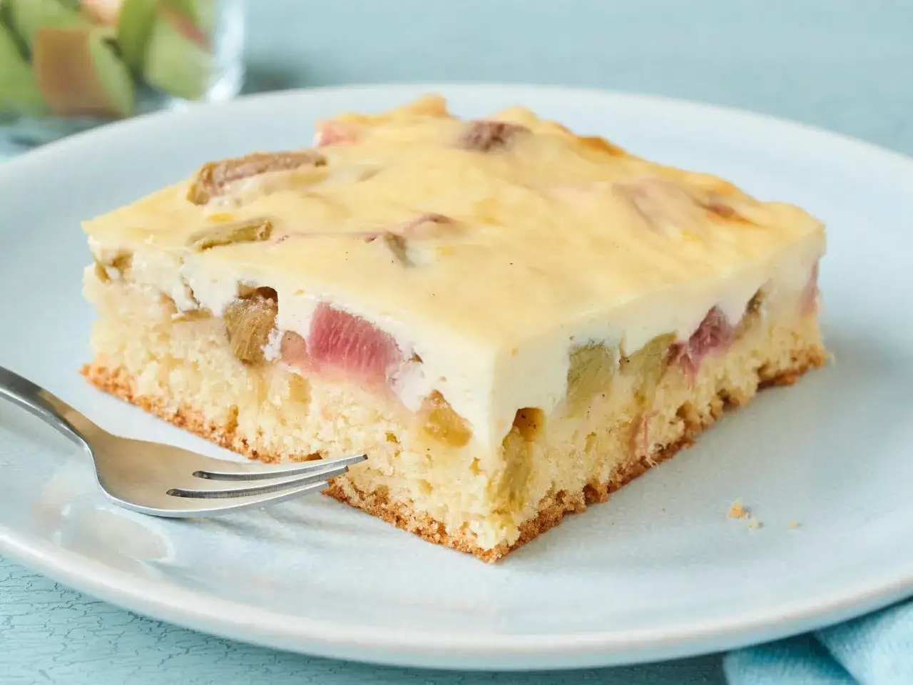Ein St&uuml;ck rhabarberkuchen schnell und saftig auf einem Teller, mit einer Gabel bereit zum Genuss.