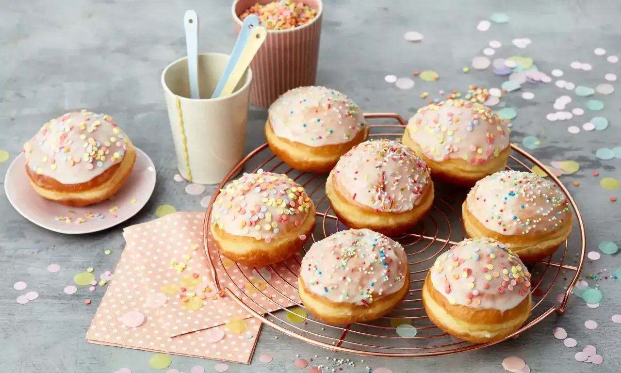 A festive spread of donuts with a sweet berliner glasur, adorned with colorful sprinkles, ready for a celebration.