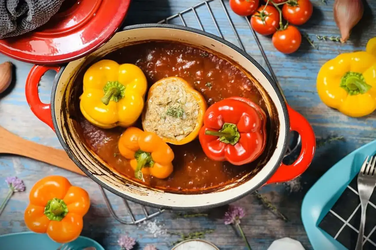 Gef&uuml;llte Paprika in einer roten Schmorpfanne, ein k&ouml;stliches Gericht, das Lust auf mehr Paprika Rezepte macht.