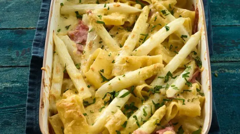 Ein cremiger Spargel Nudel Auflauf mit Schinken und frischer Petersilie, goldbraun überbacken.