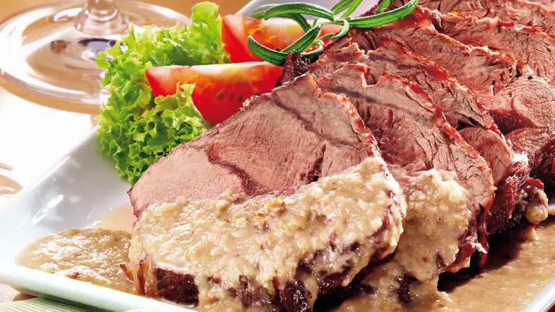 Saftiger Sauerbraten, perfekt für Ihr nächstes Sauerbraten Rezept, serviert mit frischem Salat und Tomaten.